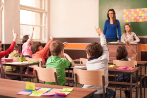 Children in elementary school are raised hand in clasroom